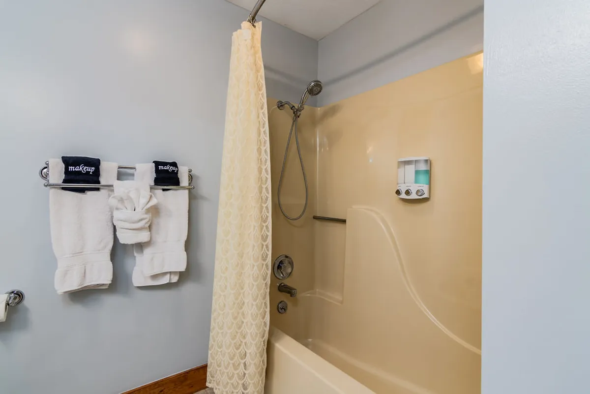 A refreshing shower area featuring fluffy towels and a classic shower curtain, creating a practical and relaxing spot to clean up after outdoor adventures.